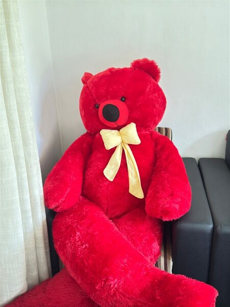 Gros ours en peluche rouge avec un ruban jaune