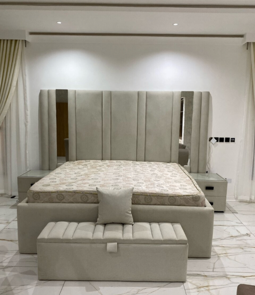 Lit beige capitonné en tête de lit