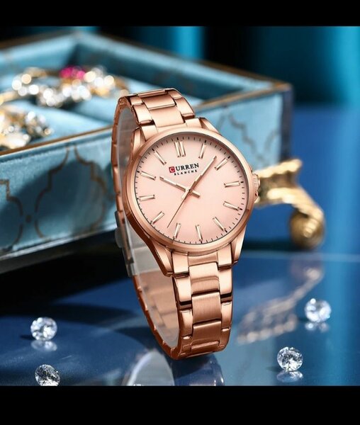 Ladies curren watch with a pink face and metal starps.