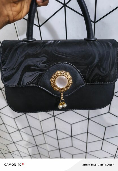 Sac à main noir élégant avec broche dorée