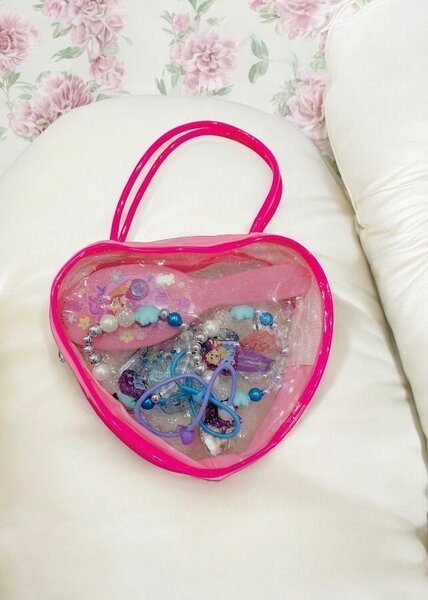 Pink bag with hair accessories and jewelry for kids.