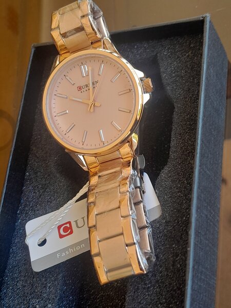 Ladies curren watch with a pink face and metal starps.